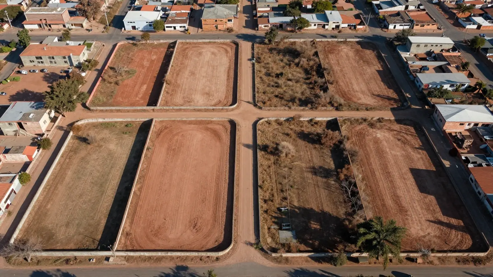 Vista aérea de lotes urbanos delimitados por muros y vías, en el borde de una ciudad